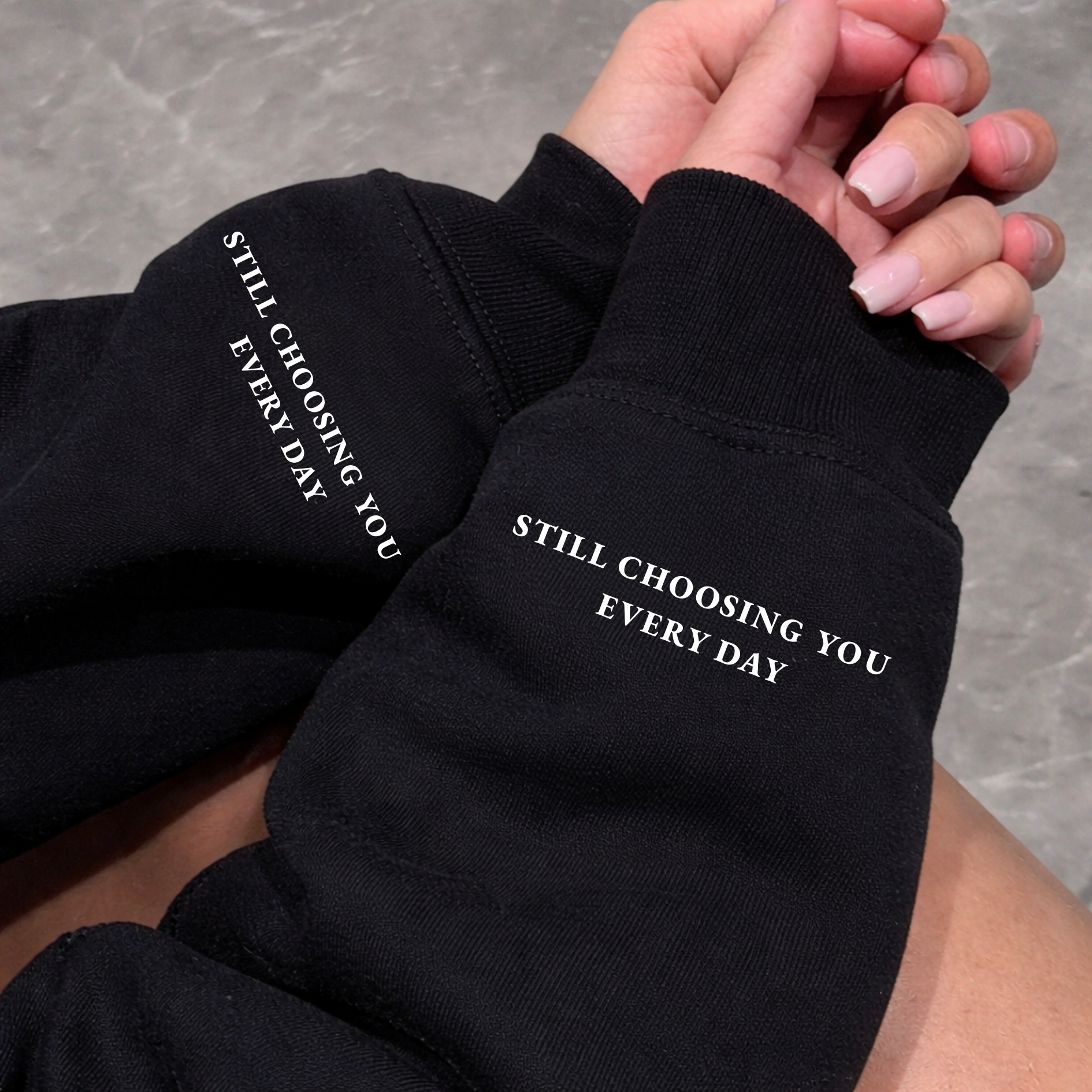 Close-up of Black Hoodie sleeve showing "Still Choosing You Every Day" text printed on left wrist cuff