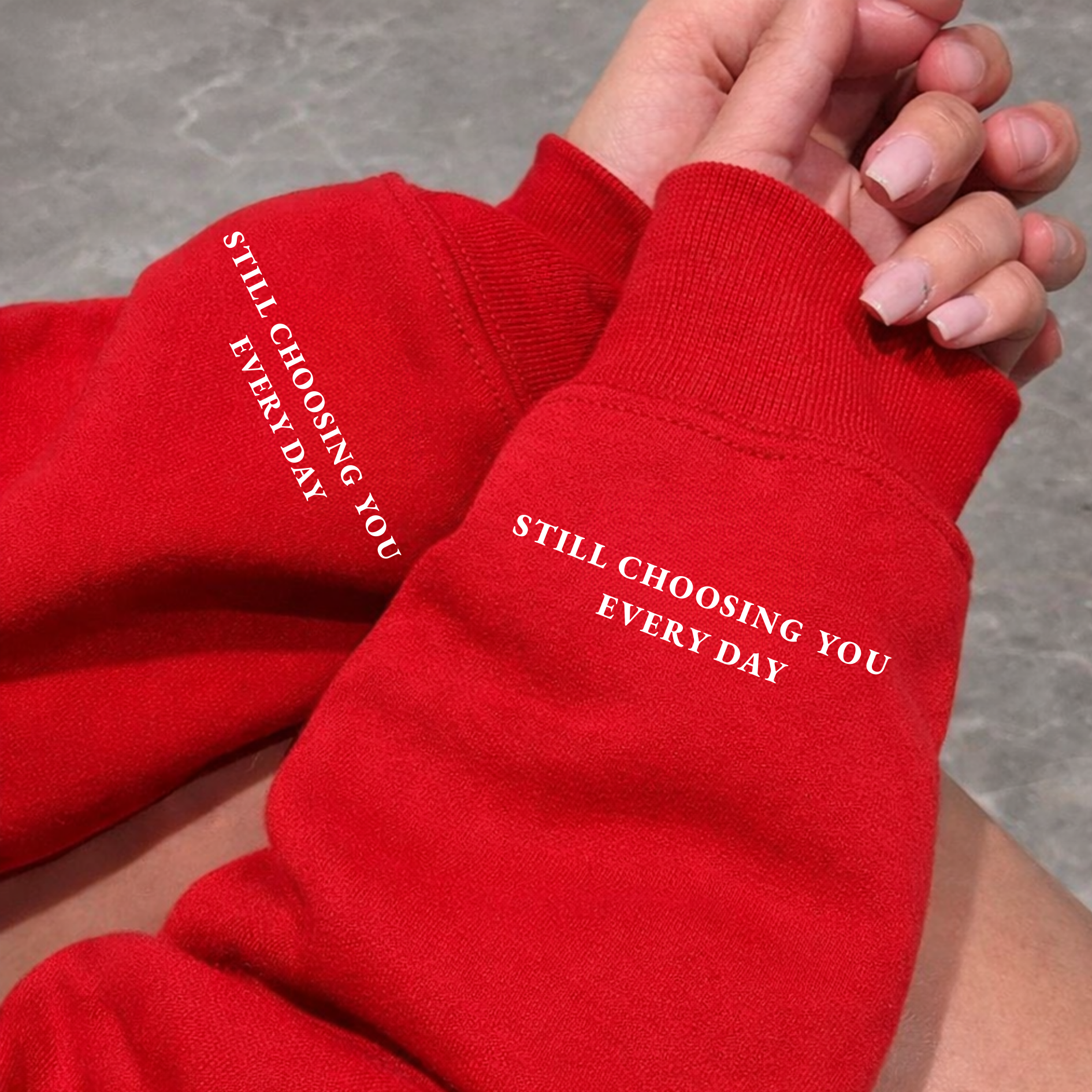 Close-up of Red Hoodie, sweatshirt sleeve showing "Still Choosing You Every Day" text printed on left wrist cuff